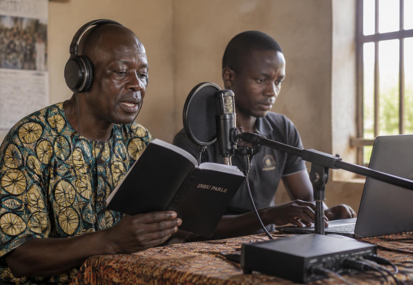 Two men recording Scripture in a local language in a simple rural studio